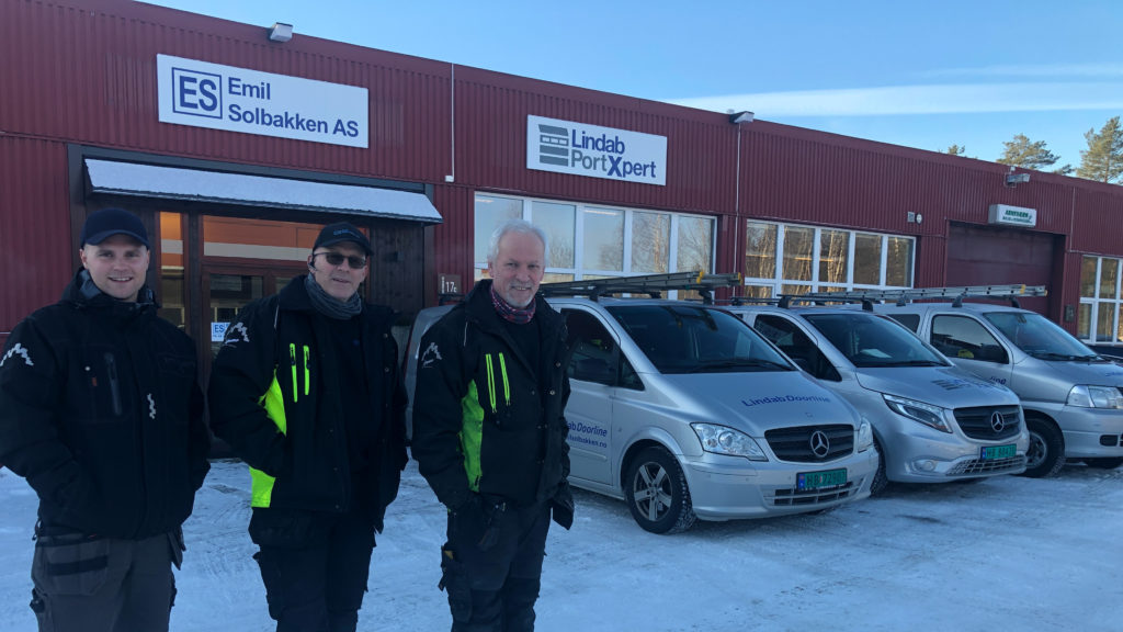 bildet viser tre menn foran bygning